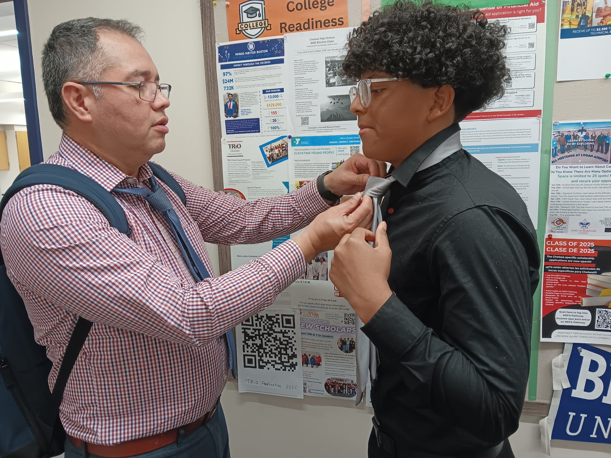Chelsea Public Schools Director of Multilingual Education Dr. Alberto Carrero helping CHS student Jose Romero tie his tie at the Mock Interview Forum